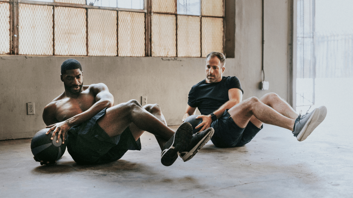 Two men performing Russian Twist ab exercise
