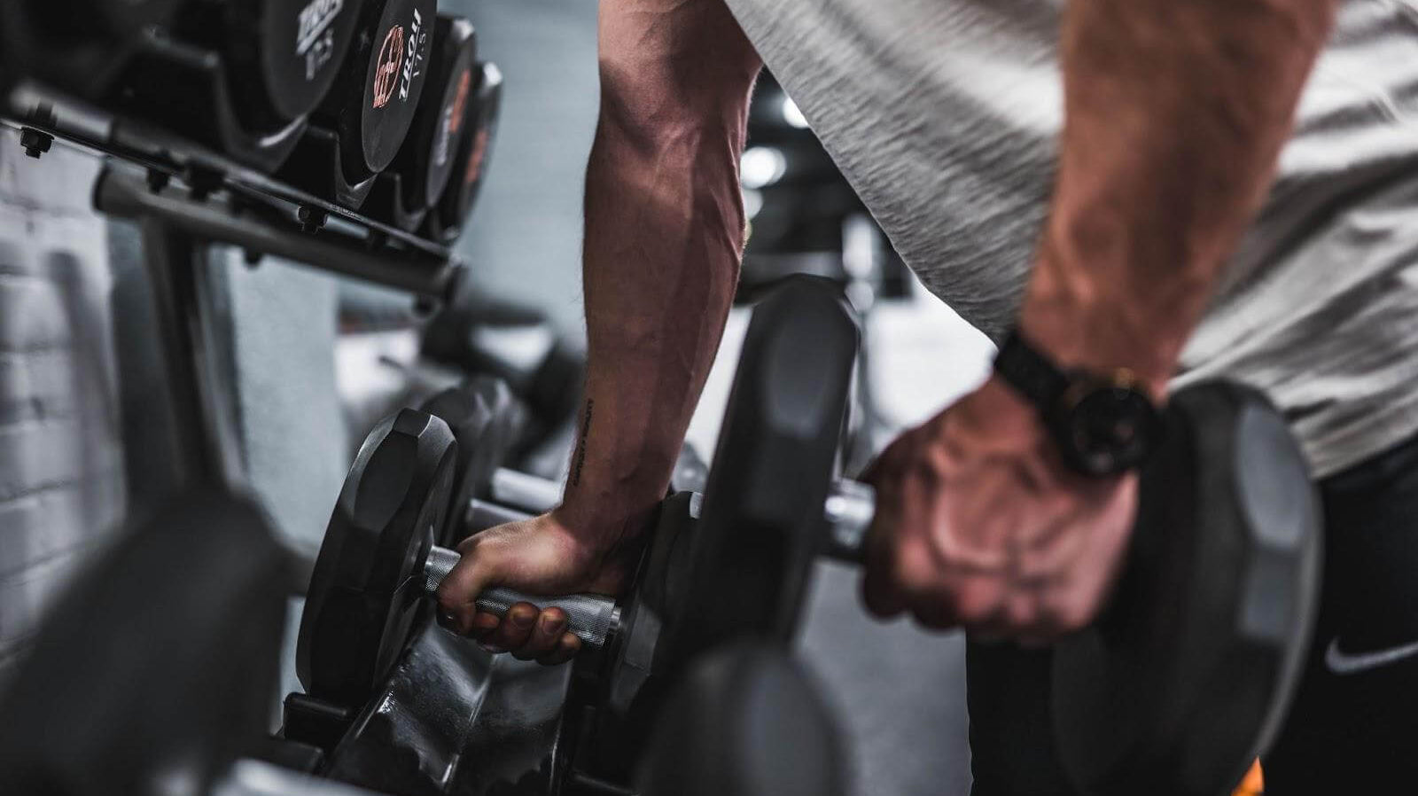 Weightlifter taking a dumbbell out the rack